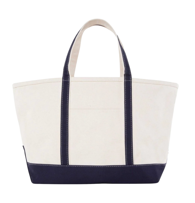 A canvas boat tote with a navy blue base and white upper part, featuring two handles and a front exterior pocket.