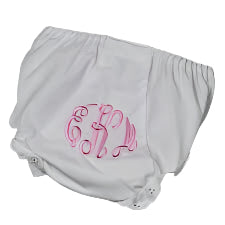 White baby bloomers with pink monogram on a wooden surface