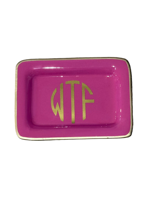 Pink rectangular dish with gold lettering on a wicker surface