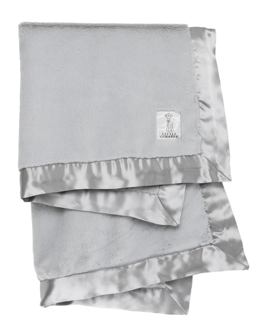 Folded silver satin blanket with a brand label on a white background